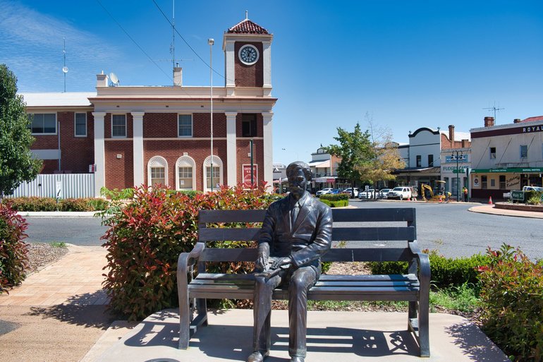 The famous faces of Grenfell and Henry Lawson writing a poem on a bench on the corner of Main and Forbes Streets