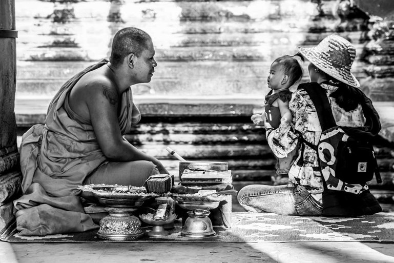 A young child receives a blessing from a Buddhist monk inside Angkor Wat