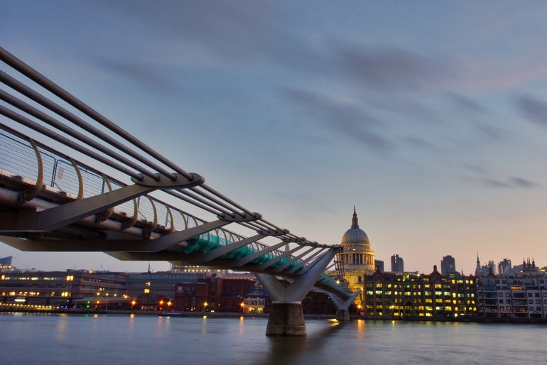 Two iconic pieces of architecture from London, the Millennium Bridge and St. Paul's Cathedral at dawn